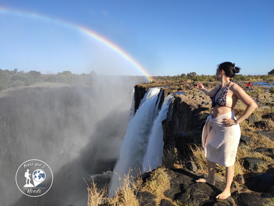 Donna che indica le cascate Vittoria ed il loro arcobaleno